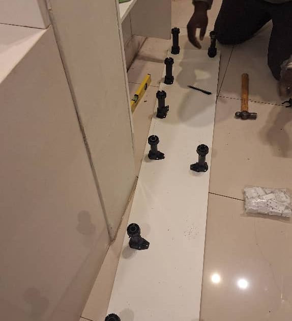 Cupboard panels and fittings laid out during a DIY-style assembly