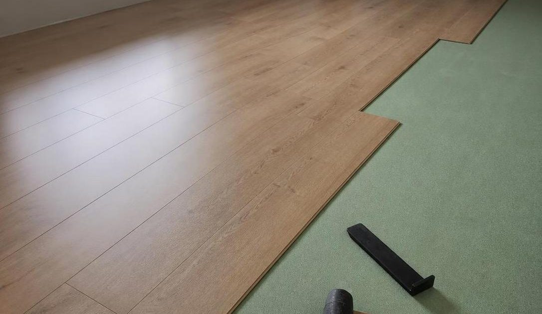 Light oak laminate flooring being installed over green underlay in a Cape Town lounge